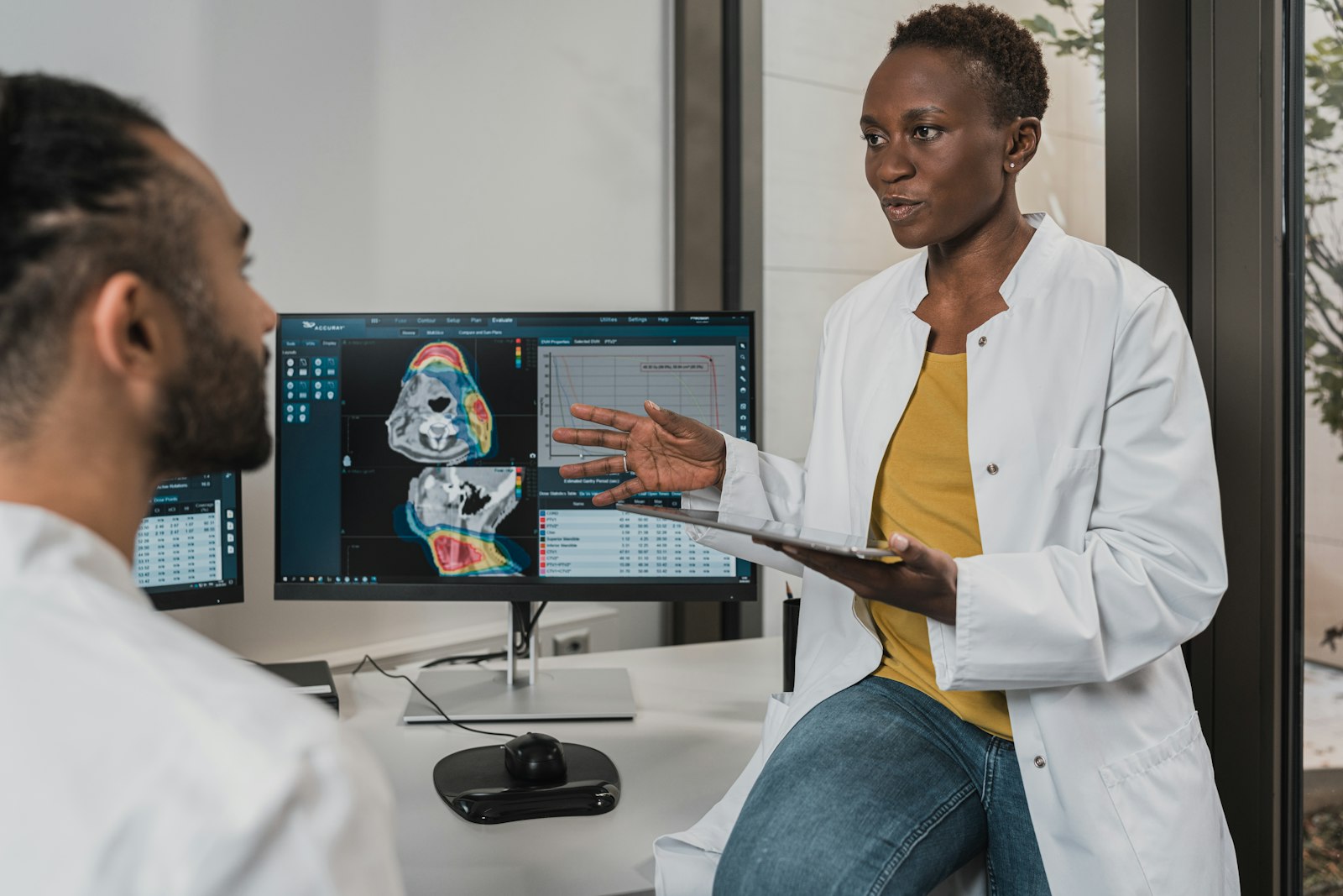 A radiologist discussing a diagnostic scan with a colleague at a reporting workstation