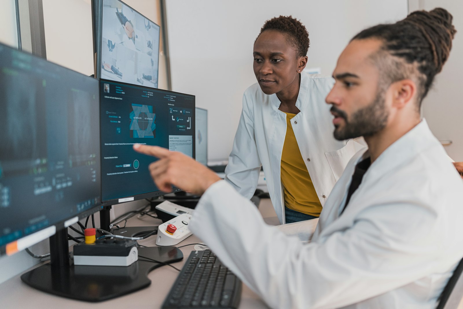 Two clinicians reviewing cross-sectional imaging on screen