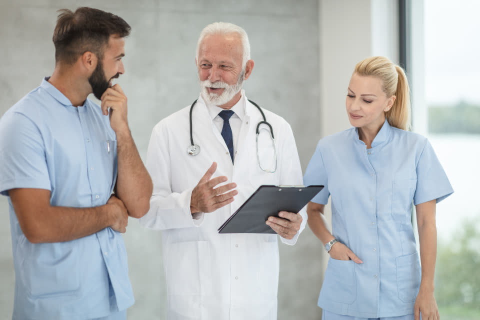 A senior consultant reviewing a patient chart with two nurses